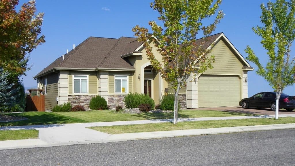 Suburban house with a wide garage door and young trees along the street